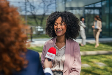 Obraz premium Smiling businesswoman giving an interview to a reporter