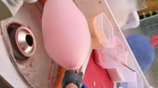 A close-up of the process of making cotton candy in a park using a special machine. vertical