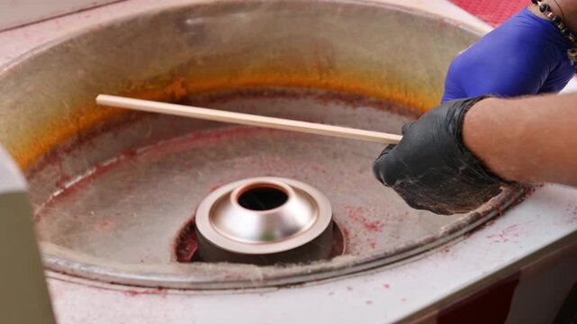 A close-up of the process of making cotton candy in a park using a special machine.