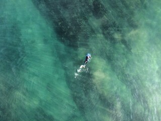 Fototapeta premium An explorer on a surfboard rests amidst the vast ocean, capturing the peaceful and adventurous spirit of surfing surrounded by the mesmerizing beauty of blue waters.