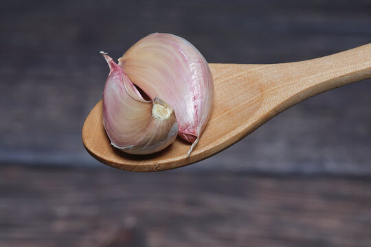 two garlic cloves on a wooden spoon, healthy food