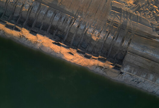 Extensive earthworks and material extraction are underway at site.truck is seen transporting sand or gravel along the water surface. project involves building infrastructure to connect channel, rial v