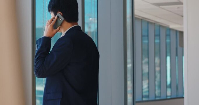Happy man, phone call and contact in office by window, insight and review proposal at real estate company. Asian person, smartphone and realtor with smile, listen and feedback at property agency