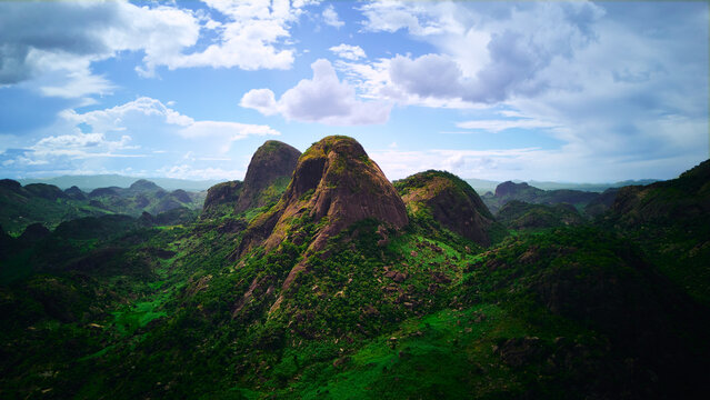 Aerial view of lush green mountains and valleys under a partly cloudy sky, creating a vibrant contrast between the verdant landscape and the rocky peaks, Vinales, Cuba.