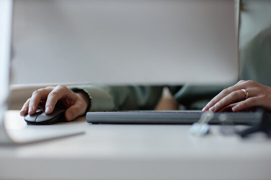 Close up of young adult woman using computer mouse and keyboard at desk, working on digital tasks. Suitable for remote work, office productivity, technology service marketing
