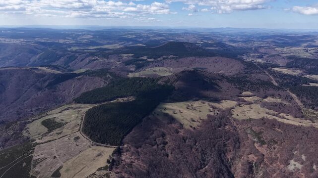 Drone at high elevation reveals hills transitioning into cultivated fields and open land in Montpezat-sous-Bauzon, Ard&egrave;che, France