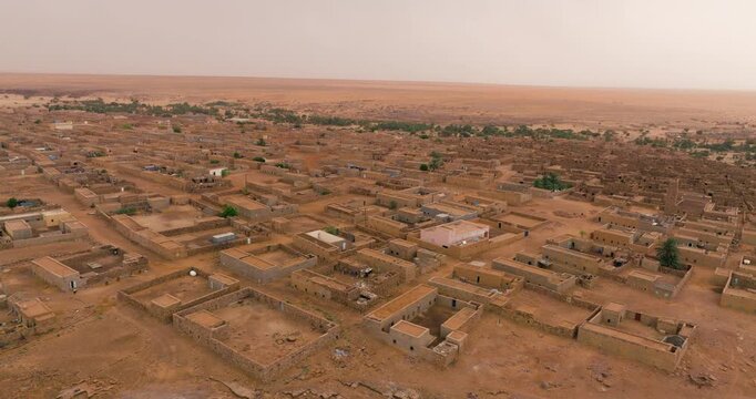 Earth-toned Settlement In Desert Town Of Ouadane In Adrar Plateau Of Mauritania. aerial sideways shot