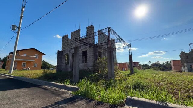 Ground level view of structural framework under construction beside modern finished houses in a developed village at Camella Homes Alfonso Cavite Philippines