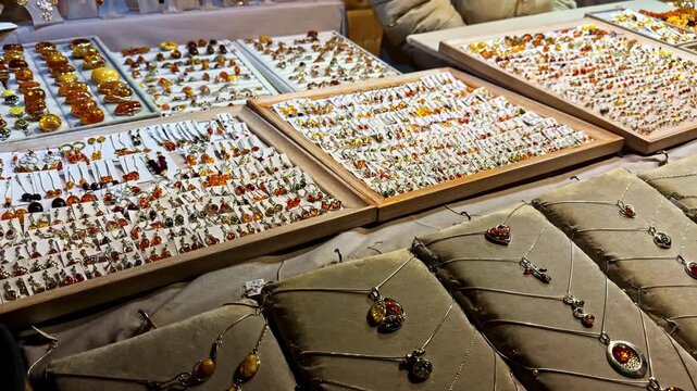 Pan shot of handcrafted necklaces and pendants displayed on cushions at a market stall.
