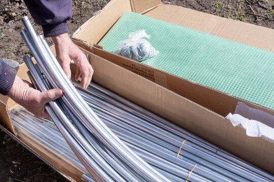 Greenhouse kit unpacking metal pipes and covering material for assembly
