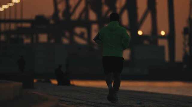 Athletic man running on a urban embankment at sunrise