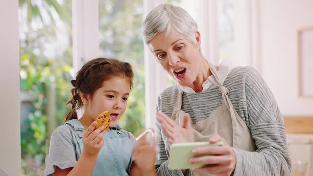 Grandmother, girl or phone for video call with cookie in kitchen, family fun or baking update for chat. Wave, talk or senior woman with happy child for weekend bonding, mobile or show biscuit in home