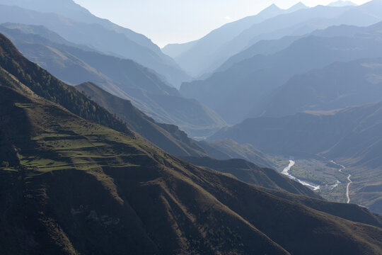 A view of blue mountain ranges, hidden by a light haze.