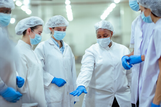 Industrial workers discuss production workflow and prepare for shift inside food factory. Concept shows teamwork, communication, safety compliance, and efficient manufacturing operations.