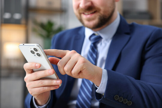 Man using modern smartphone in office, closeup