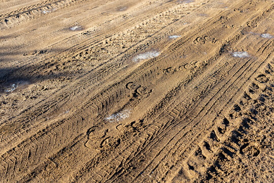Vehicle marks visible. Industrial outdoor scene featuring muddy tire tracks and loose gravel