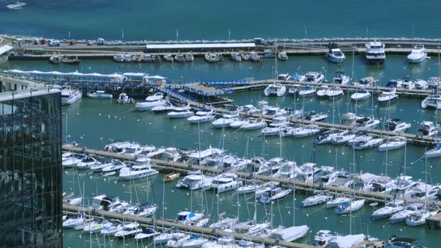 Aerial view of numerous white boats nestled in the marina's tranquil waters, contrasting with the azure sea and the bustling pier, Punta del Este, Departamento de Maldonado, Uruguay.