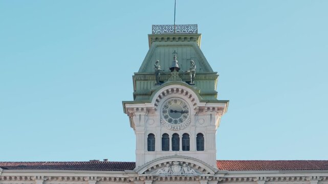 The historic Town Hall clock tower with the bronze statues Micheze and Jacheze in Piazza Unita d Italia in Trieste Italy under a clear blue sky in the afternoon