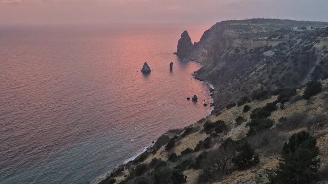 Sunset coastline sea stacks over dramatic pink water and towering cliffs at Cape Fiolent