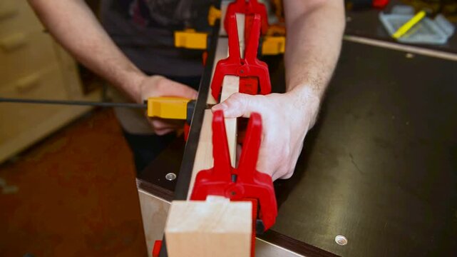 Skilled focused craftsman hands assembling clamps, securing bonding wooden boards. Precise woodworking, hands on expertise on mechanical setup, joinery artisan workspace, professional technique.