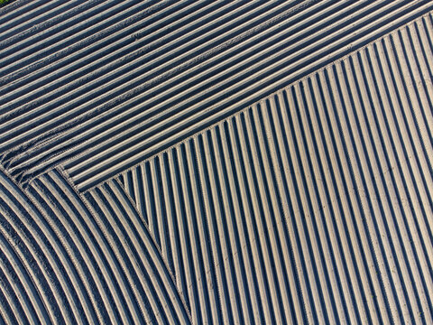 Aerial view of a mesmerizing tapestry of plowed fields creating stark diagonal patterns across the landscape, Arrien, Overijssel, Netherlands.