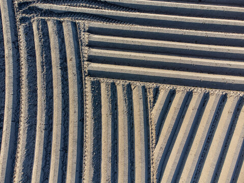 Aerial view of a geometrically patterned field with parallel furrows creating a textured landscape under soft light, Arrien, Overijssel, Netherlands.