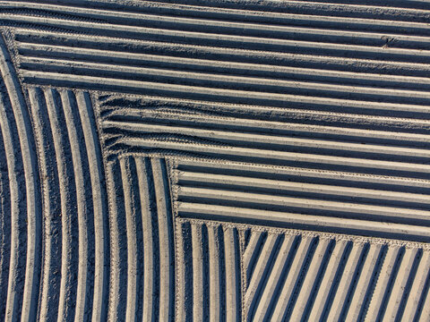 Aerial view of furrowed fields creating geometric patterns in contrasting earth tones, a testament to cultivated land, Arrien, Overijssel, Netherlands.