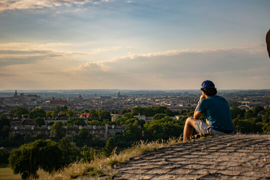 people at sunset admiring the panorama of Krakow from the Krak Mound