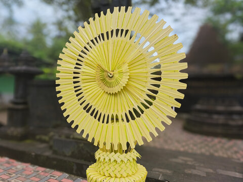 Balinese Janur Palm Leaf Circular Ornament Handcrafted Traditional Ritual Decoration with Intricate Woven Base Cultural Art Close Up Outdoor Background
