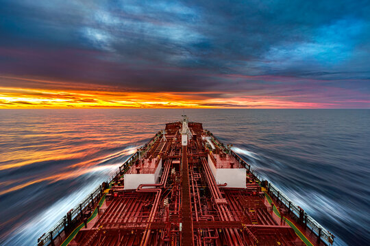 High angle view of a large oil tanker vessel deck with red pipes sailing in the deep blue calm ocean