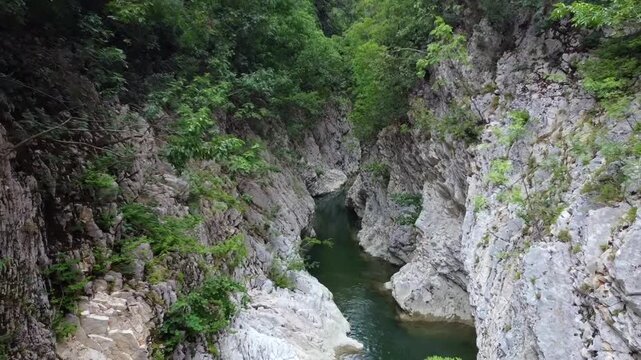 Cinematic drone shot of the deep Acheron river canyon in Epirus, Greece. High-angle view of the steep cliffs and turquoise water at the legendary Gates of Hades. Ideal for history and nature films.
