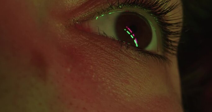 Macro shot of a brown woman eye in red and green lighting. Concept of optics and vision, eye health, the beauty and media industries, technical and IT innovations, nightlife themes.