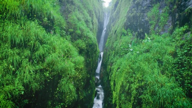 4K Aerial shot of Saatsada waterfall flowing in narrow valley of Sahyadri Hills in Maharashtra, India. Waterfall flowing between two mountain creek during monsoon. Scenic nature view.