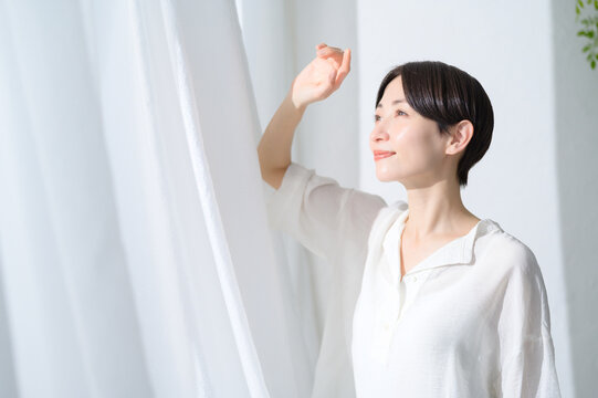 窓からの日差しを浴びる日本人女性