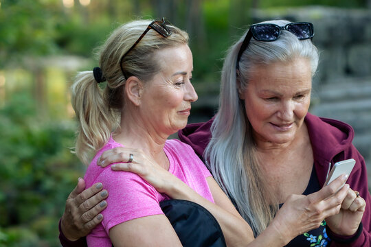 Smiling senior woman sharing smart phone with female friend at park
