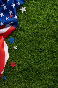 American vertical flag draped on green grass with red white and blue star decorations creating a patriotic Fourth of July mood for summer backyard celebration and holiday commemoration