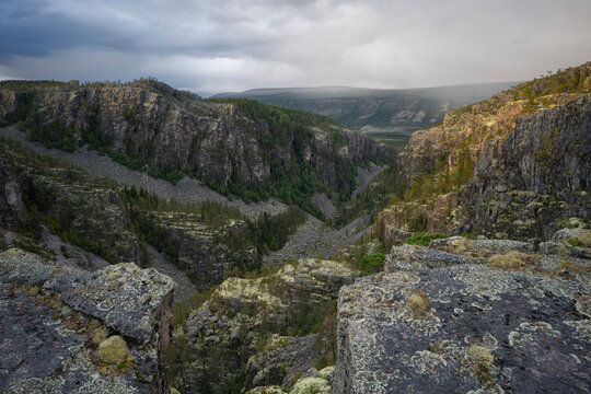 Drone point of view of lichen covered rocky surface of canyon against cloudy sky