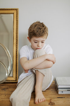 Sad boy grieving while sitting on table at home