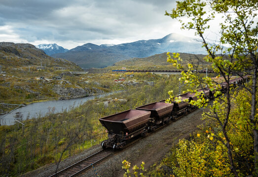 Empty wagons of coal stationed on tracks against scenic mountains
