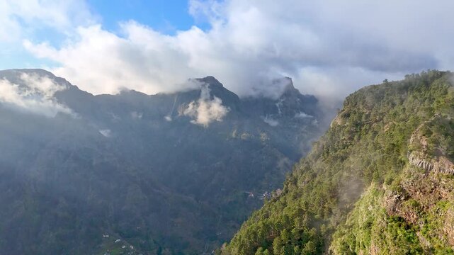 Portugal, Madeira, Curral das Freiras, Eira do Serrado. Thick mist rolls over the jagged volcanic peaks to reveal a village nestled deep within the central mountains of Madeira. 