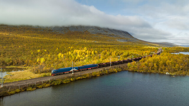 View of coal train passing through lake amidst lush greenery against sky