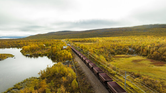 Drone view of freight train moving through lush green landscape against sky