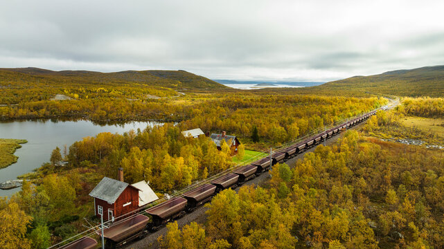 Coal train passing through village on green landscape against sky