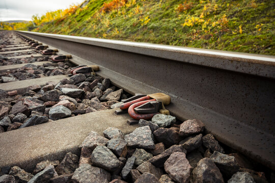 View of elastic rail clip attached on railway tracks amidst stones