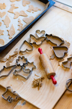 High angle view of different variety of cookie cutters kept on cutting board with rolling pin