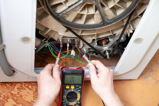 Checking the heater in a washing machine with a multimeter on the floor