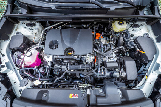 Close-up of modern car engine compartment with internal combustion engine and hybrid components for automotive maintenance and technology concepts.