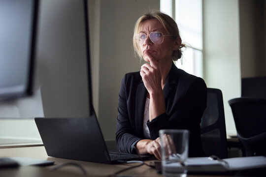 Thoughtful mature female business expert working at office desk