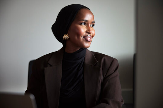 Smiling female business expert wearing headscarf looking away