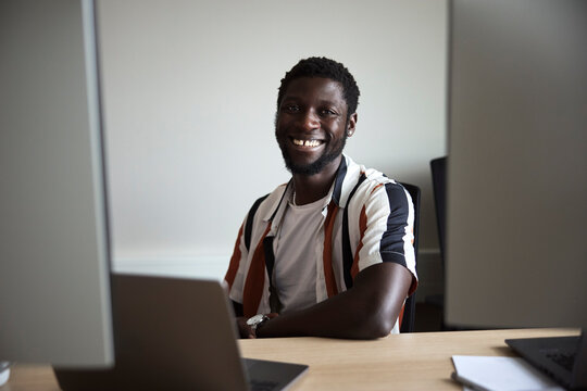 Portrait of smiling male tech professional sitting at desk in office